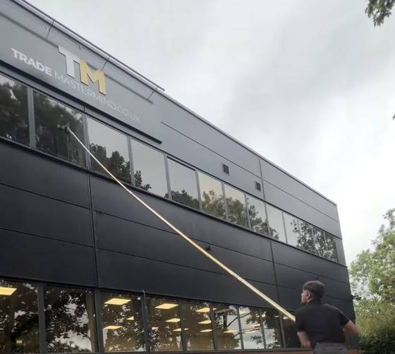 A building facade being soft washed with a pole